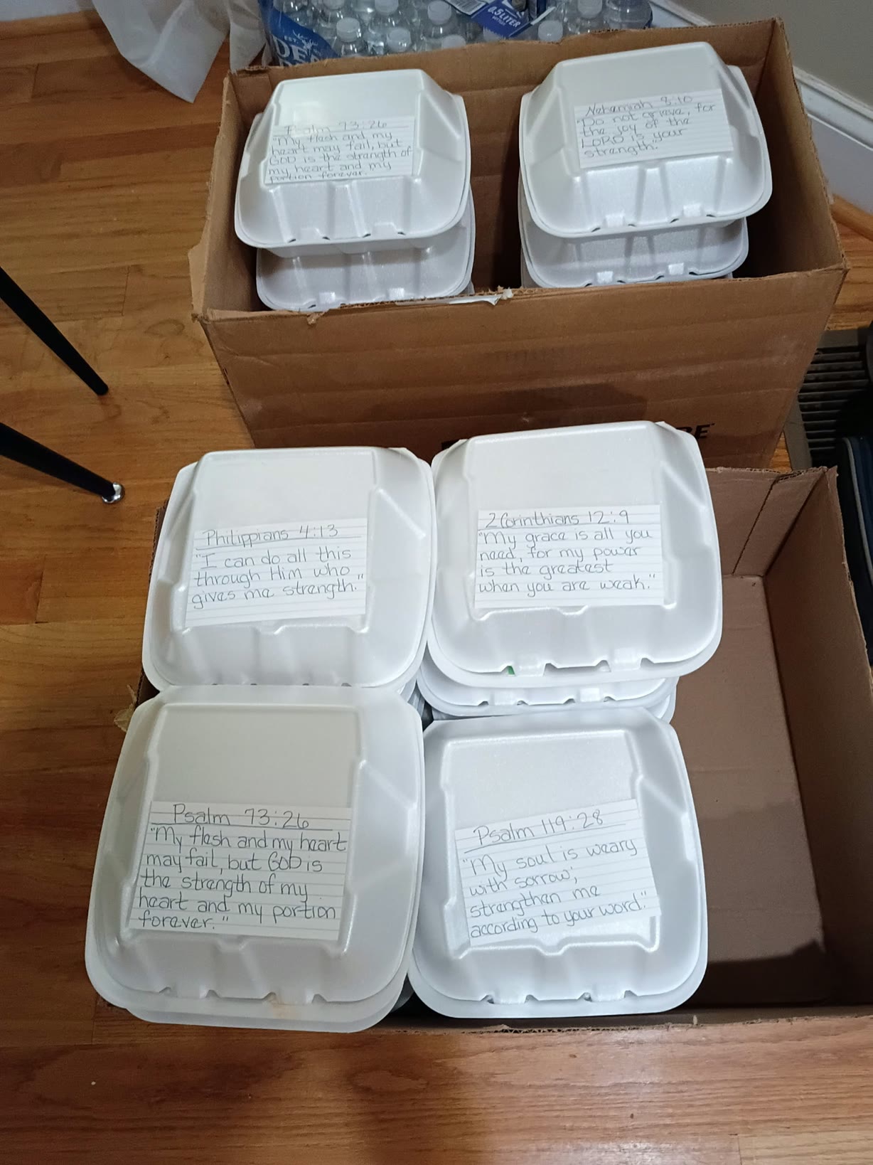Packed meal containers in boxes with handwritten scripture cards